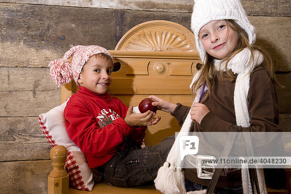 Zwei Geschwister-Kinder mit Apfel in einer Wanderhütte