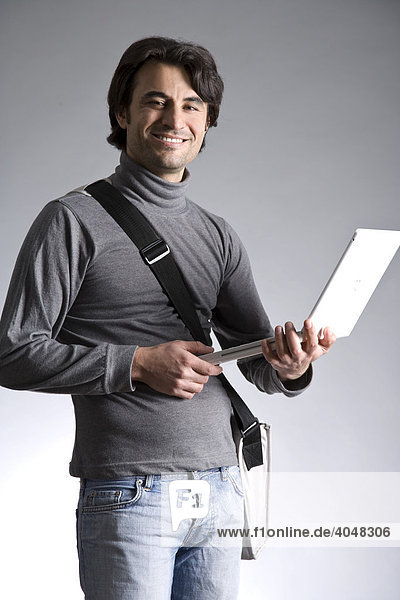 Young man with a bag  holding a laptop