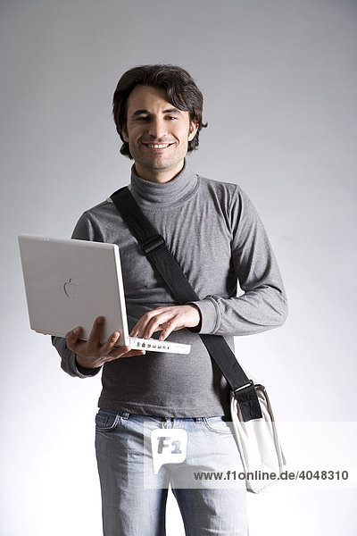 Young man with a bag  holding a laptop