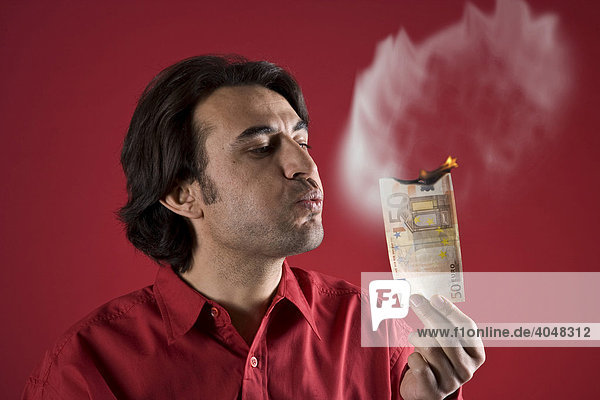 Man holding a burning 50-Euro bill