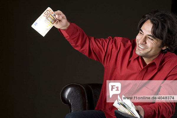 Young man waving a 50 Euro bill  happy about his full wallet