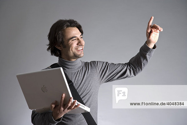 Young man with a bag  holding a laptop  waving