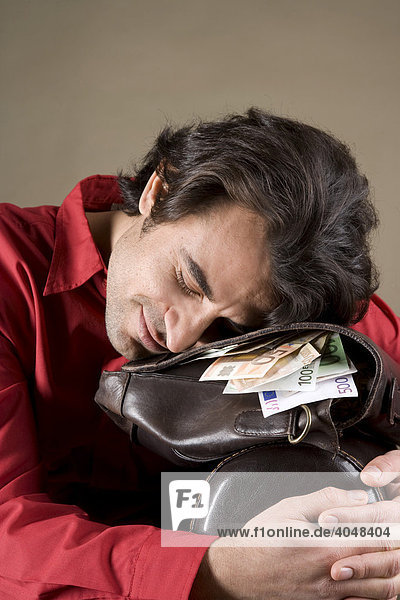 Young  content man resting on his bag full of money