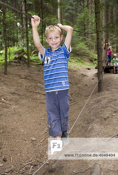 6-year-old boy balancing on a rope in a forest
