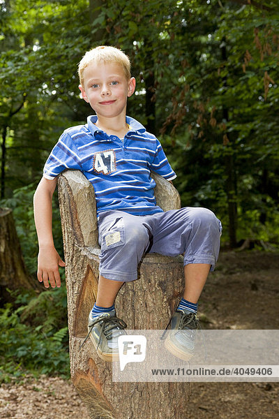 6-year-old boy sitting on a tree trunk  carved to resemble a throne