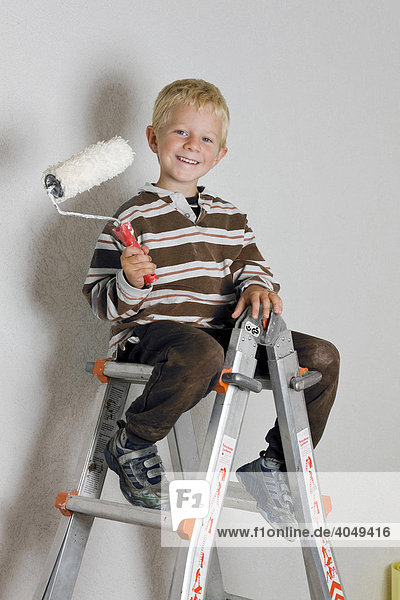5-year-old boy sitting on a ladder  holding a paint roller