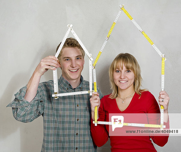 A young couple  22-year-old man and 20-year-old woman  holding house-shaped folding rules