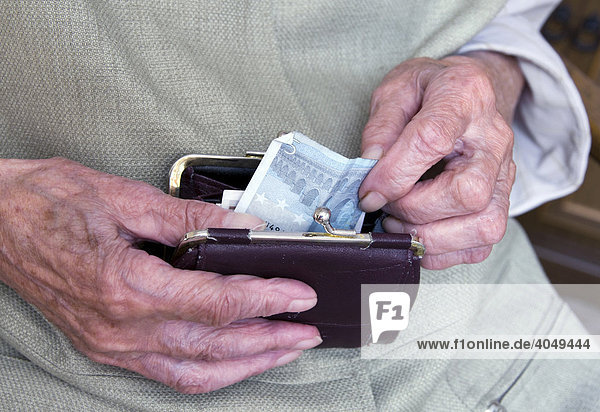 An old lady taking a banknote from her purse  detail