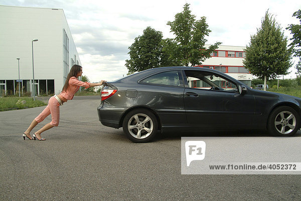 Junge Frau in einem rosa Anzug schiebt ihren Wagen an