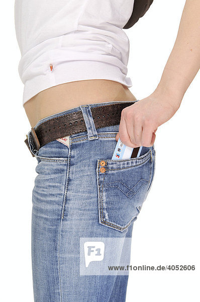 Frau steckt Kreditkarte in Hosentasche von Jeans