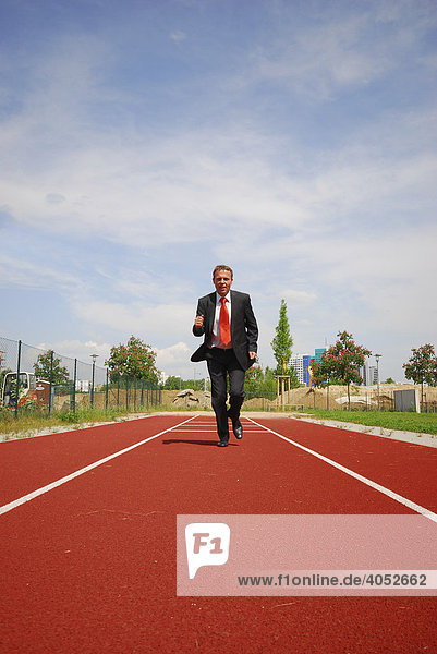 Geschäftsmann im Anzug rennt auf einer Laufstrecke auf das Ziel zu  zielstrebig  ehrgeizig