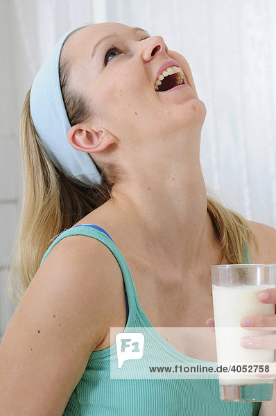 Young blond woman drinking a glass of milk
