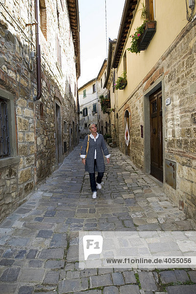 Woman walking through the old alleys of a typical old wine village  Chianti  Province of Florence  Firenze  Tuscany  Italy  Europe