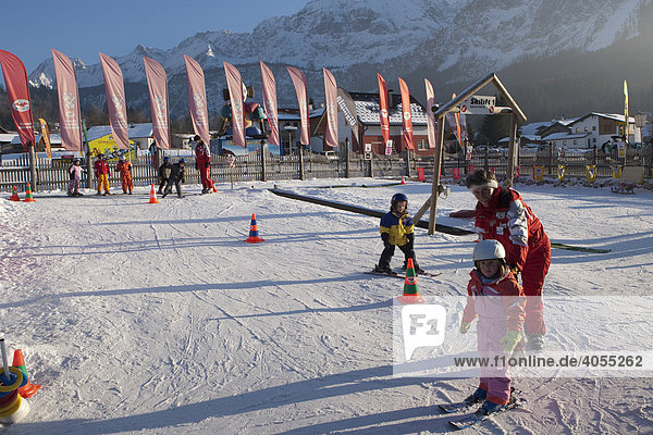 Kinder werden von einer Skilehrerin in einem Anfängerkurs in einer Skischule unterrichtet  hinten die Zugspitze  Ehrwald  Tirol  Österreich  Europa