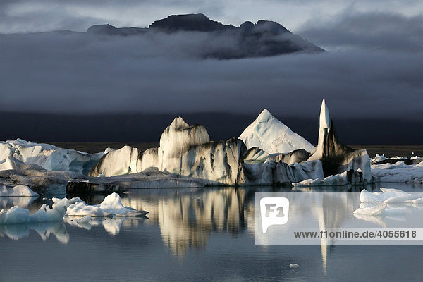 Schwimmende Eisberge  die mit schwarzer Lava-Asche gefärbt sind  in der Gletscherlagune Jökulsarlon des Gletschers Vatnajökull  Island  Europa