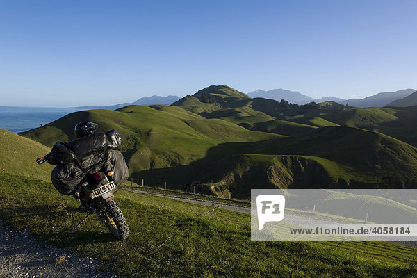 Schwer bepacktes Enduro Motorrad in einer grünen Hügellandschaft  Kaikoura Range  Südinsel  Neuseeland