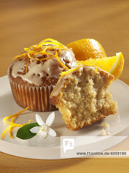 Coffee-orange Muffins with icing and garnished with zests of an orange  in front of orange wedges
