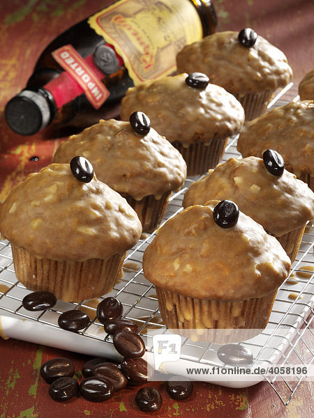 Coffee liqueur muffins on a tray garnished with coffee beans in front of a bottle of coffee liqueur