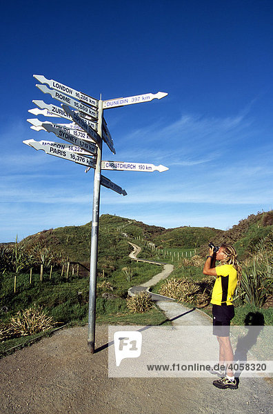 Tourist taking a photo of a direction signpost  Punakaiki  Pancake Rocks  South Island  New Zealand