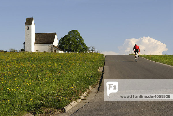 Kirche  Straße mit Rennradfahrer  Racebiker  Steinkirchen  Chiemgau  Bayern  Deutschland  Europa