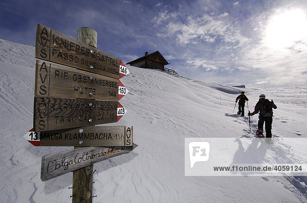 Sign post at Kniebergsattel or Knieberg Saddle  snowshoe hikers hiking to Alpe Nemes Mountain  High Puster Valley or Alto Pusteria  Bolzano-Bozen  Dolomite Alps  Italy  Europe