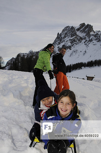 Parents pulling children on a sled on the Pietrarossa Mountain,  High Puster Valley or High Puster Valley or Alto Pusteria,  Bolzano-Bozen,  Italy,  Europe