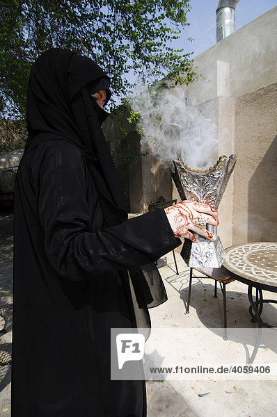 Frau mit Hennamalerei hält Weihrauchgefäß in den Händen  Dubai  Vereinigte Arabische Emirate  Naher Osten