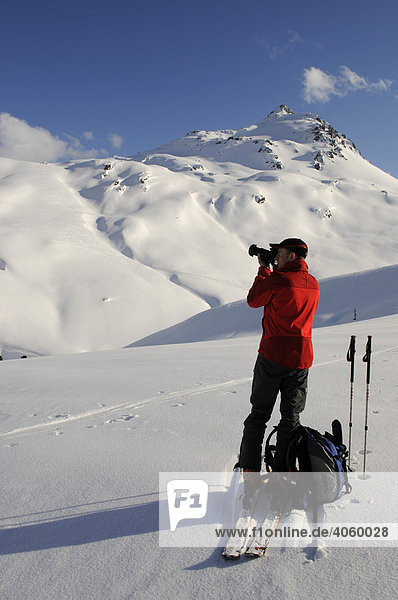 Ski hiker taking a picture during a tour up Mount Tristkopf  Kelchsau  Tyrol  Austria  Europe