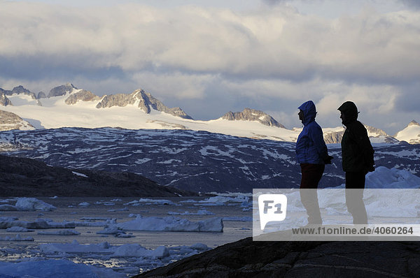 Hikers in front of icebergs in the Johan Petersen Fjord  East Greenland  Greenland