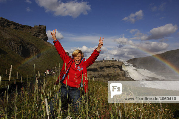 Kind jubelt unter Regenbogen am Gullfoss  Goldener Wasserfall  Island  Europa