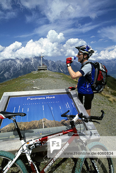 Mountain biker standing at a panorama board on Mt Asitzkopf  Leoganger Range  Salzburger Land  Austria  Europe