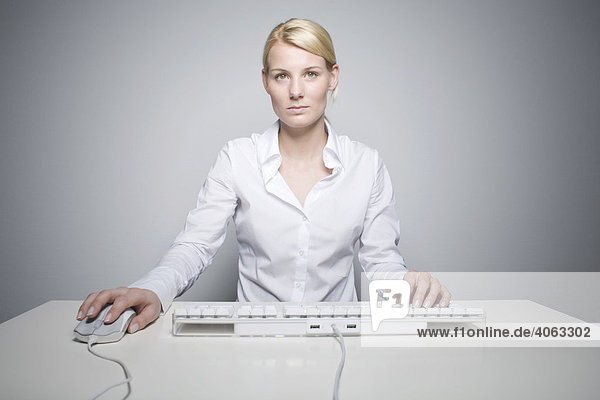 Junge blonde Frau mit Computermaus und Tastatur