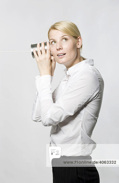 Junge blonde Frau mit Blechdosen-Telefon am Ohr