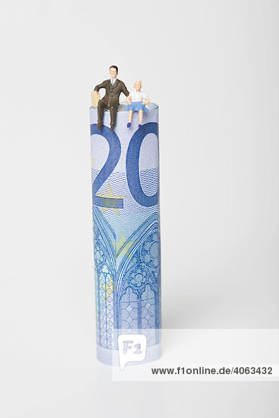 Figur eines Vaters mit Tochter sitzt auf einem 20-Euro-Schein  Symbolbild Familienkasse