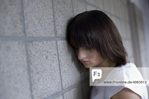Traurige junge Frau lehnt an Wand