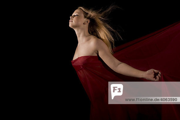 Junge blonde Frau mit rotem Tuch vor Schwarz