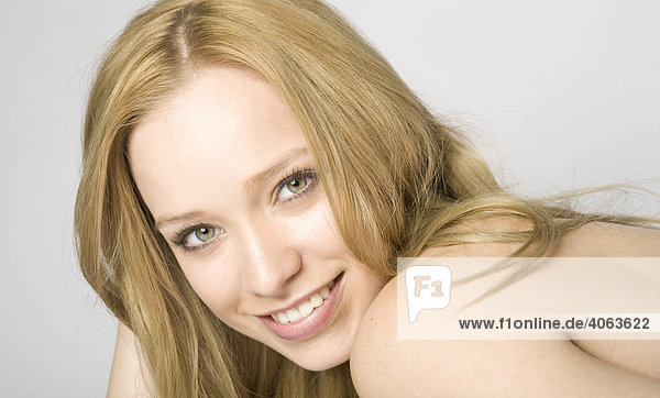 Young long-haired woman  head leaning on her hands  smiling at the camera