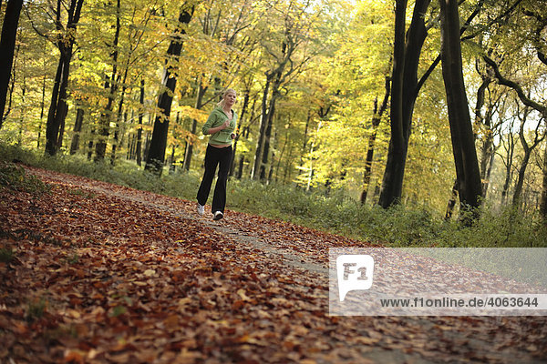 Junge blonde Frau beim Laufen im herbstlichen Wald