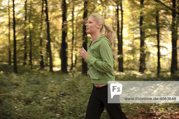 Junge blonde Frau beim Laufen im herbstlichen Wald