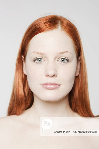 Portrait of a young red-haired woman in front of white backdrop