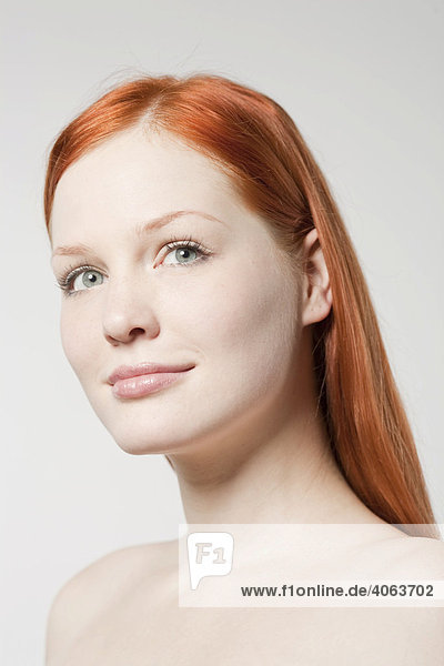 Portrait of a young red-haired woman in front of white backdrop