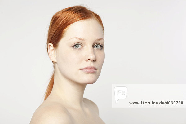 Portrait of a young red-haired woman in front of white backdrop
