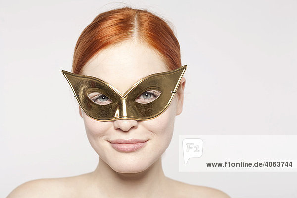 Young red-haired woman wearing a golden mask