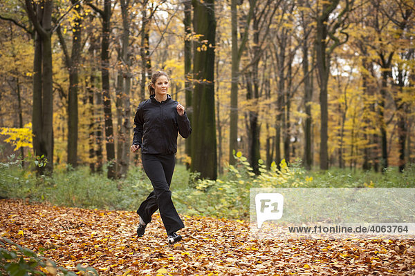 Junge dunkelhaarige Frau beim Fitnesstraining im Herbstwald