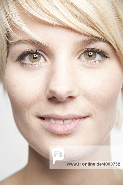 Young blond woman with short hair smiling into the camera in a friendly way