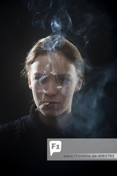 Junge Frau raucht eine Zigarette  Portrait mit Zigarettenqualm