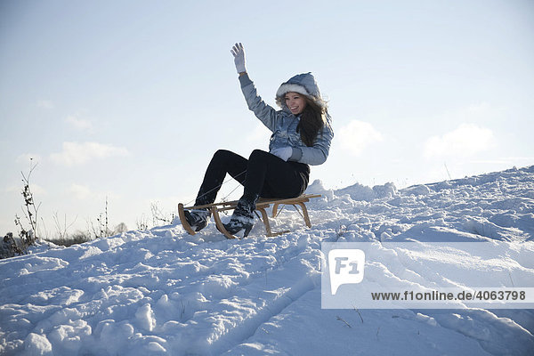 Young woman sledding in snow