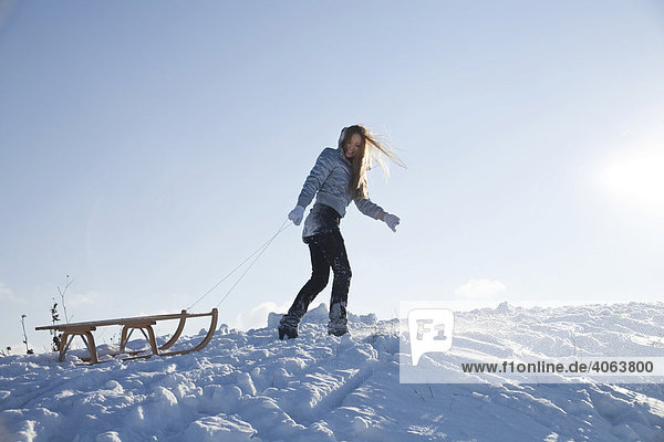 Young woman pulling a sledge in the snow