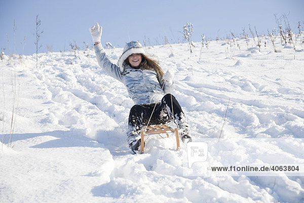Young woman on a sledge in snow