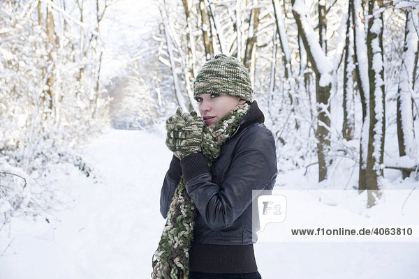 Portrait of a young woman wearing a hat and gloves in wintery landscape  freezing
